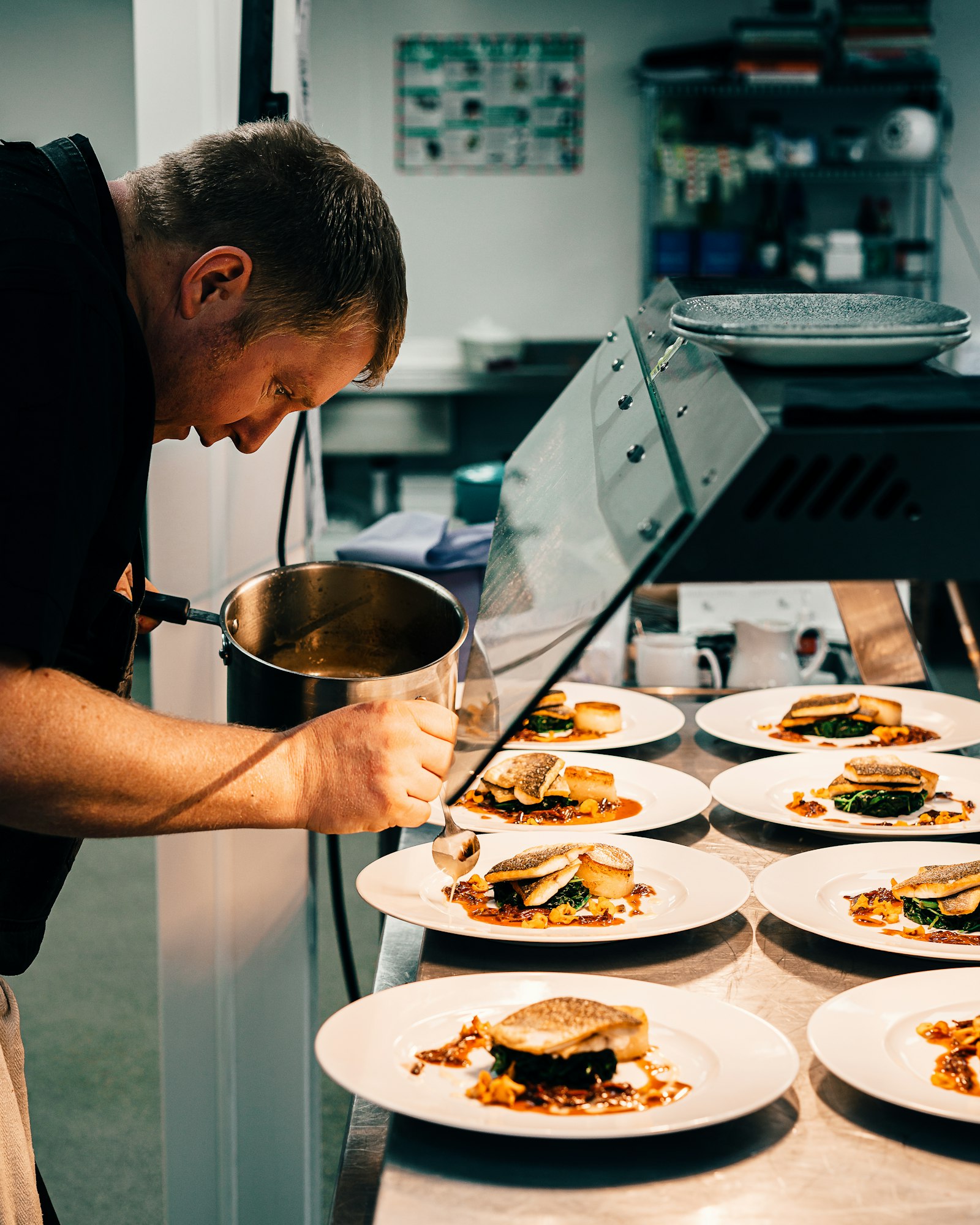 Cocinero terminando los platos en el pase de un restaurante